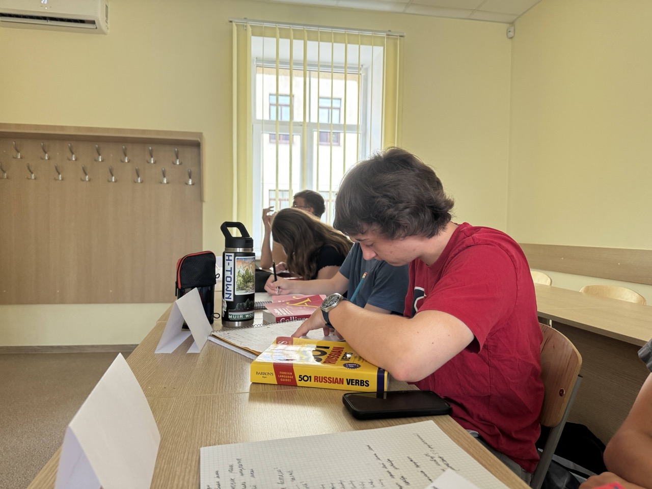 Student works at a table with a 501 Russian Verbs book
