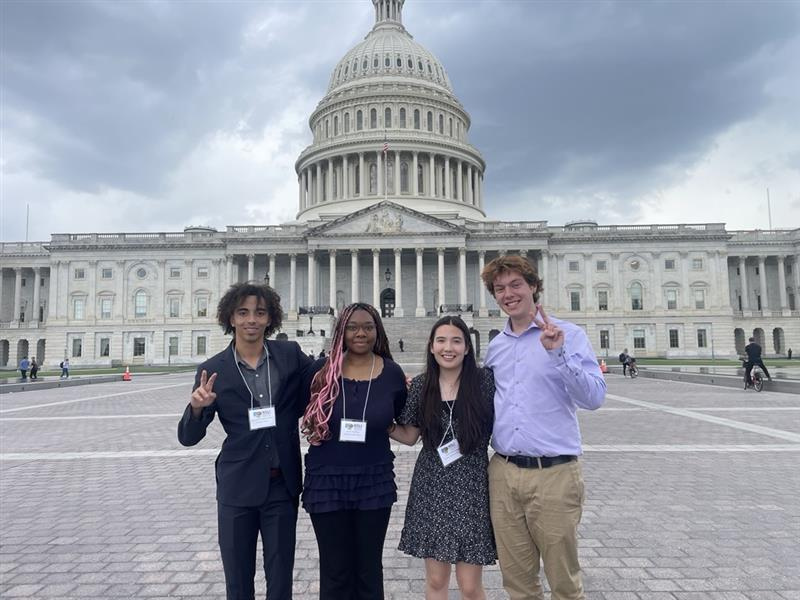 Four NSLI-Y academic year alumni pose in front of the U.S. Capitol Building as part of their re-entry orientation. Two students are holding up the peace sign.