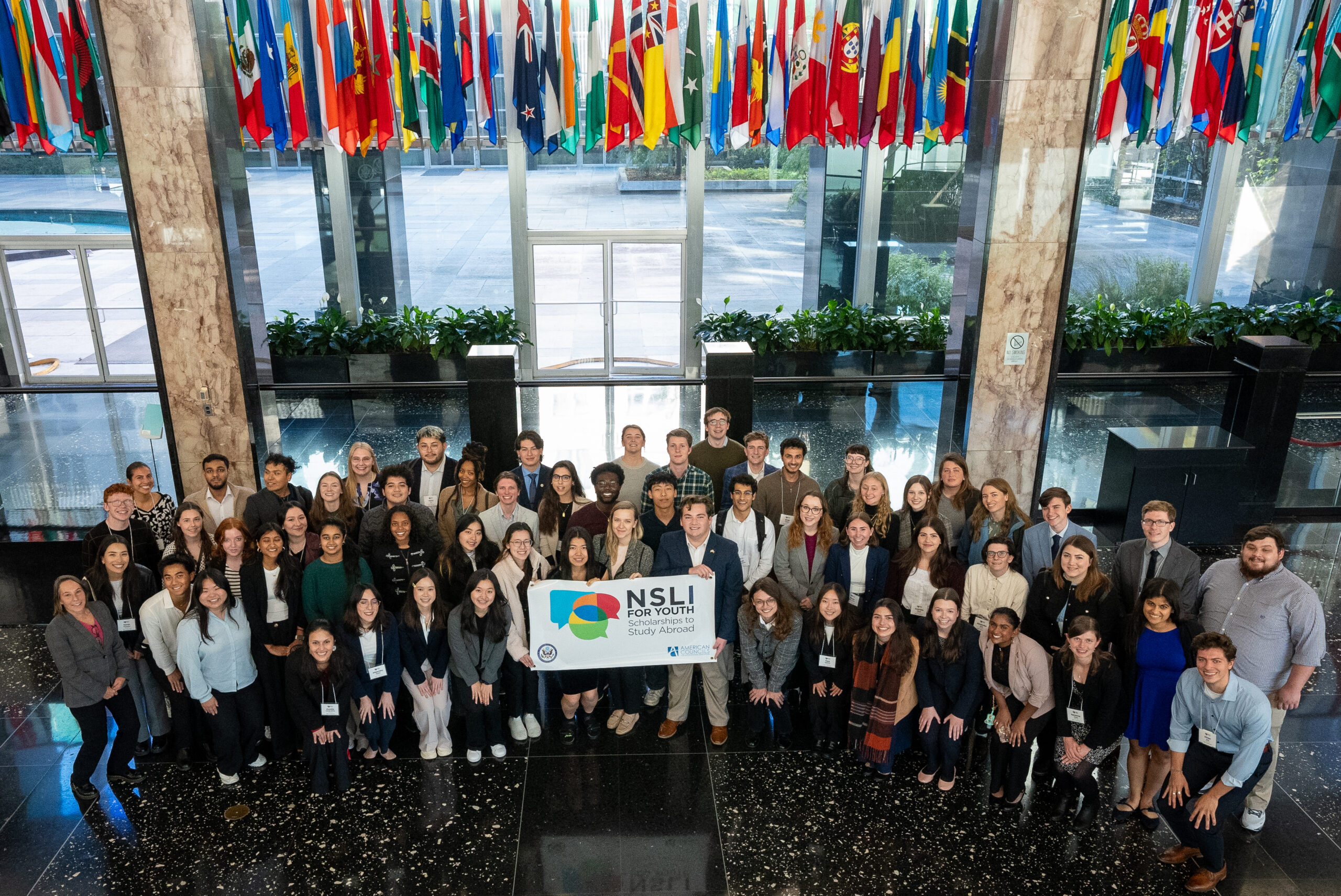 NSLI-Y alumni holding a NSLI-Y sign, in the lobby of the U.S. State Department