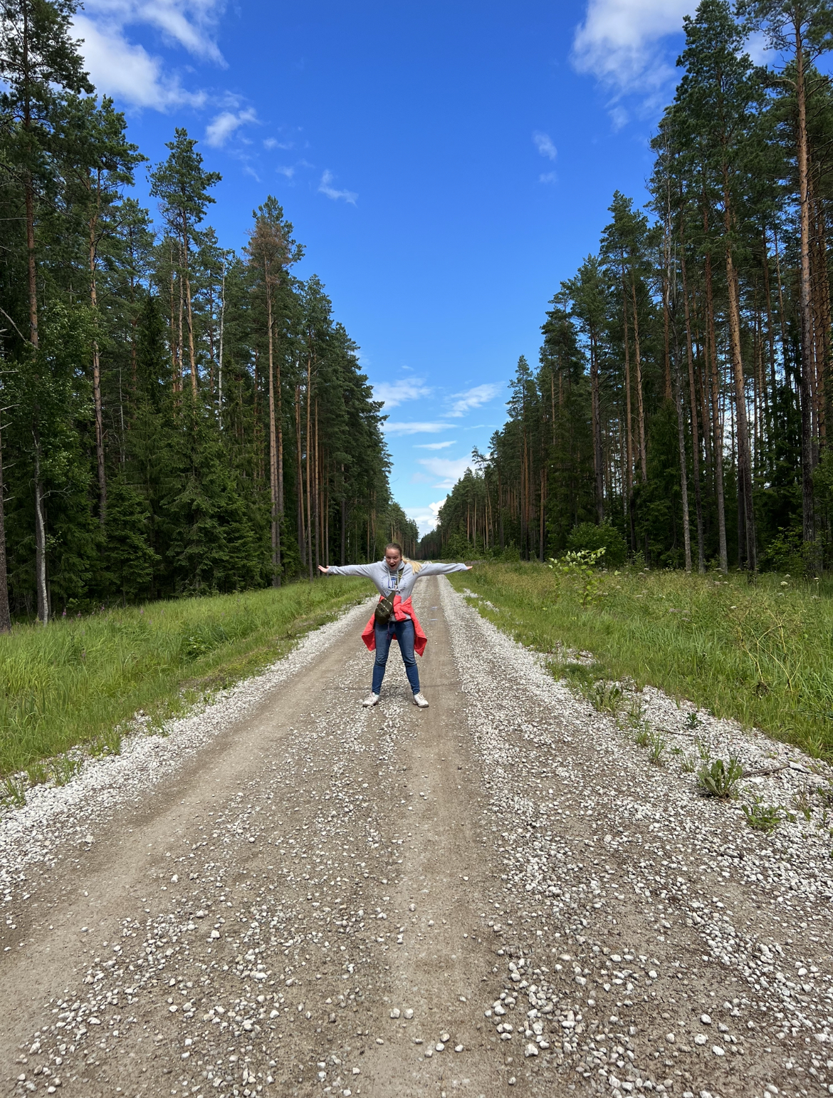 Samantha stands on a road in the forest.