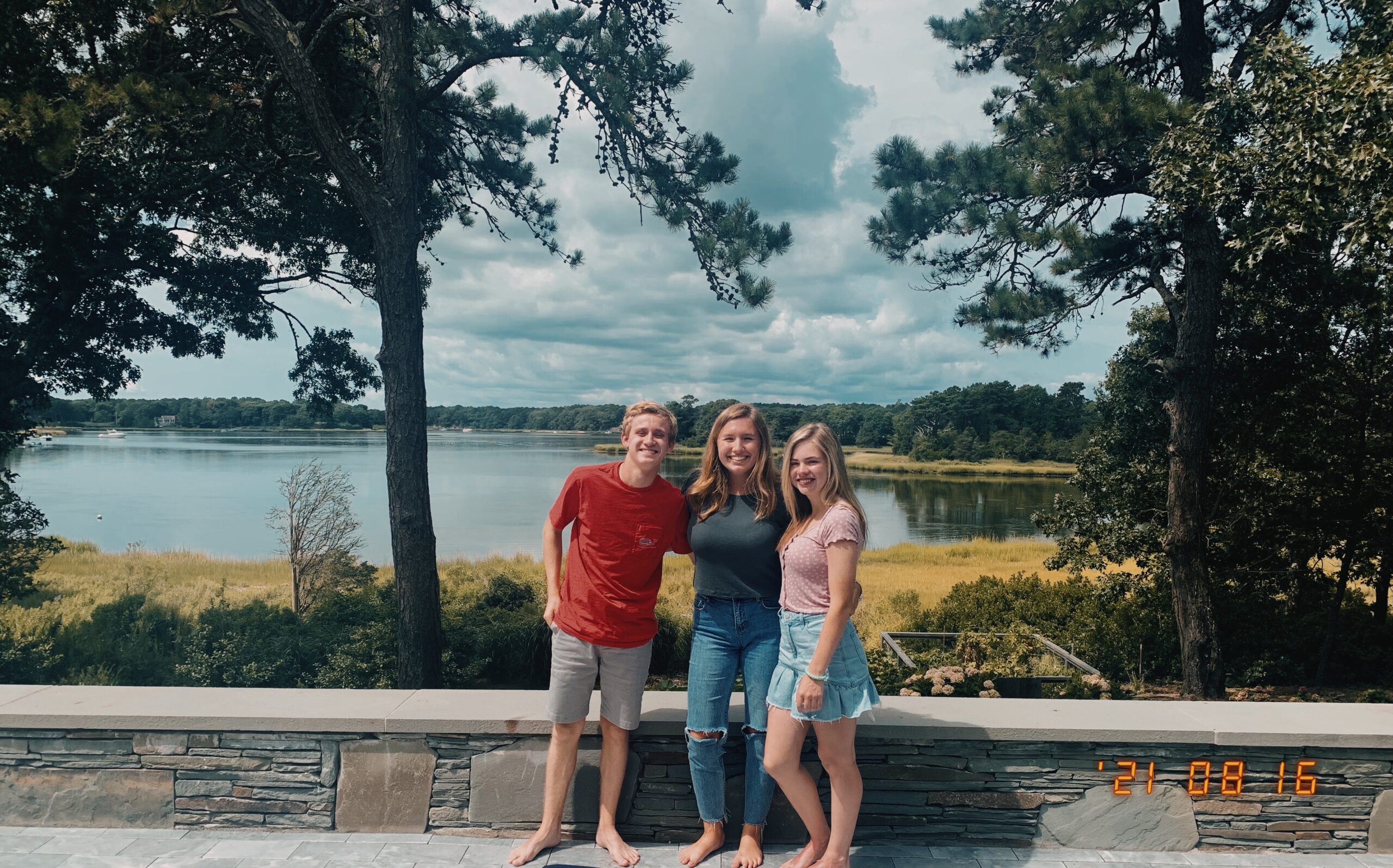 Three students pose by a lake