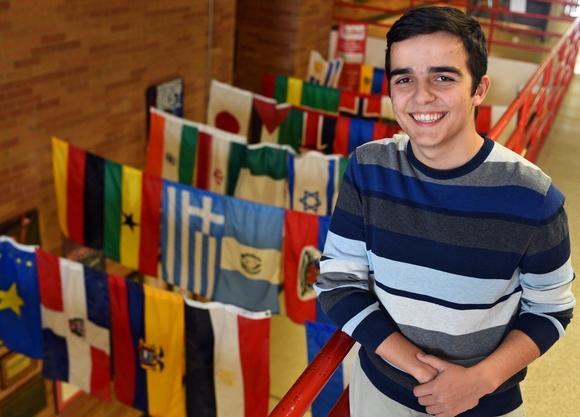 image of deni posing next to many different world flags