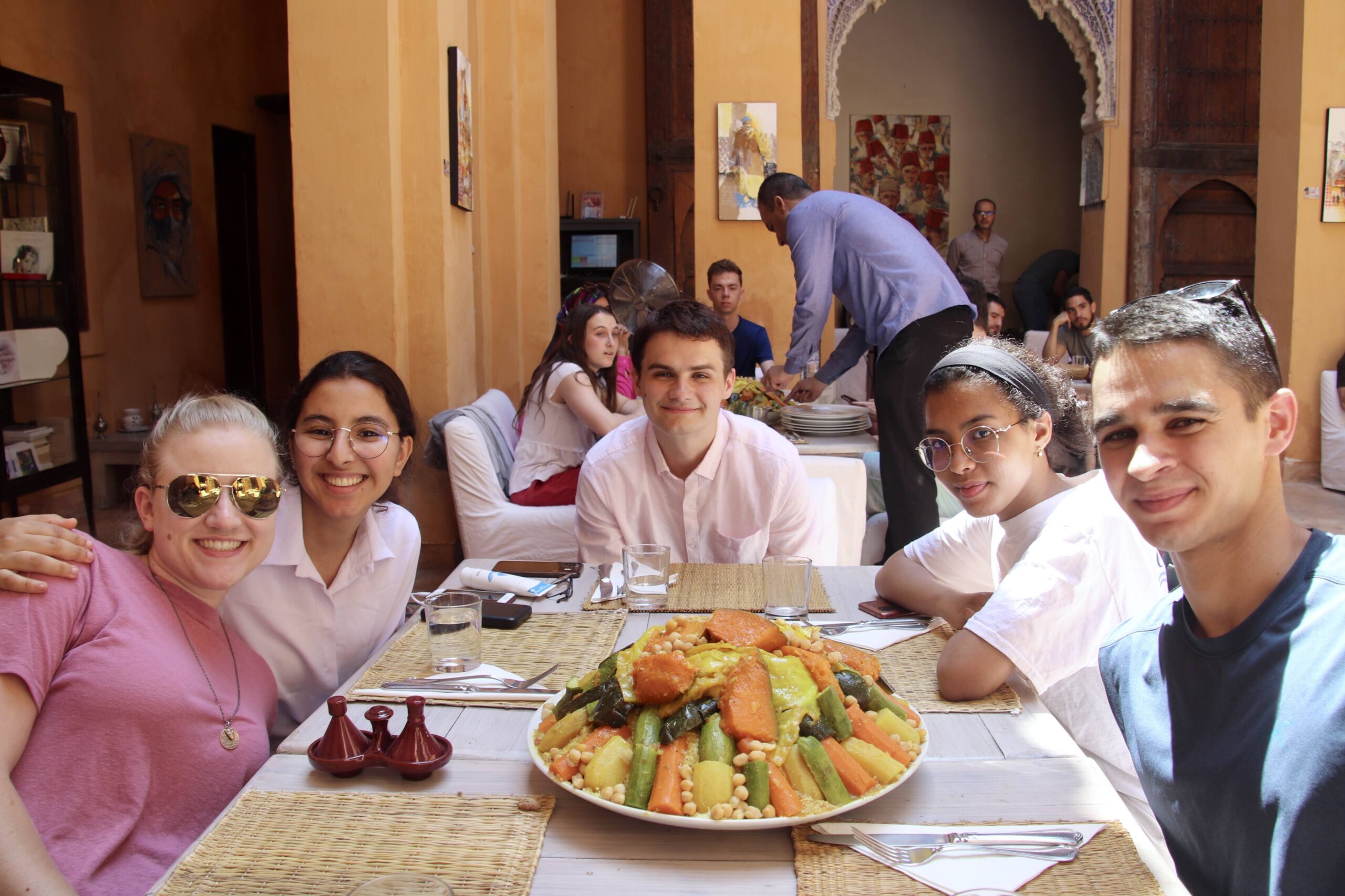 NSLI-Y students sitting around a table in front of large dish of vegetables