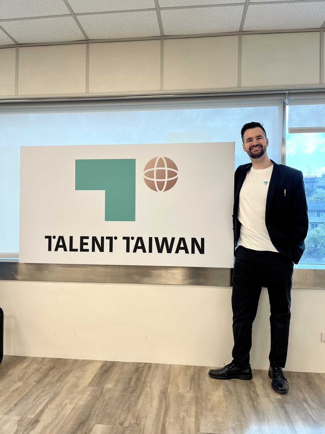 An alum poses with a Talent Taiwan sign