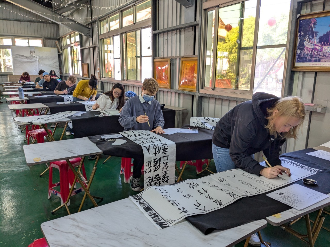 Students work on Chinese calligraphy at separate desks