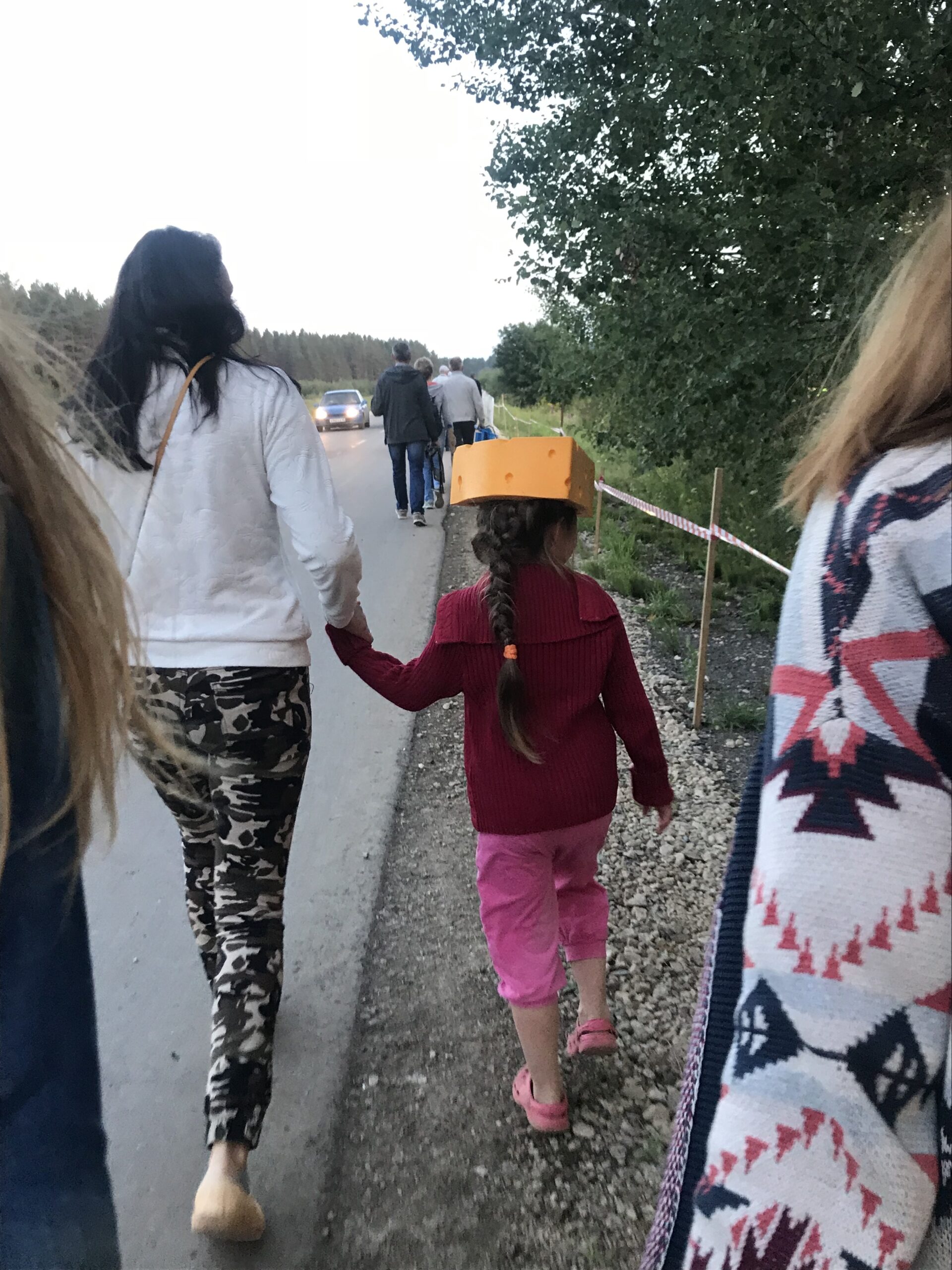 Student and host sister holding hands while wearing cheese hat.