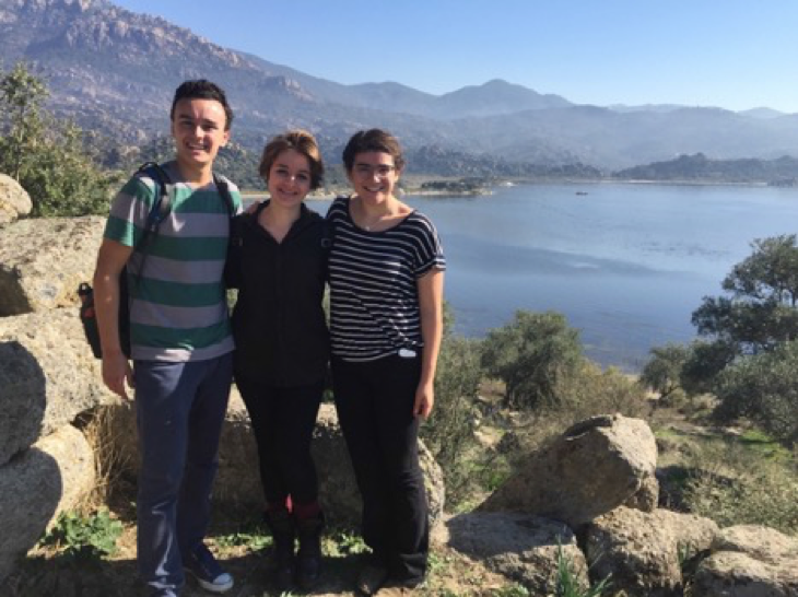 image of Gianna posing in front of a lake and mountains with two peers