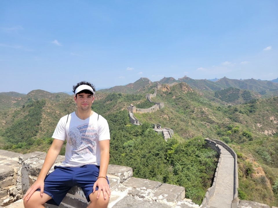 John sitting in front of the Great Wall of China