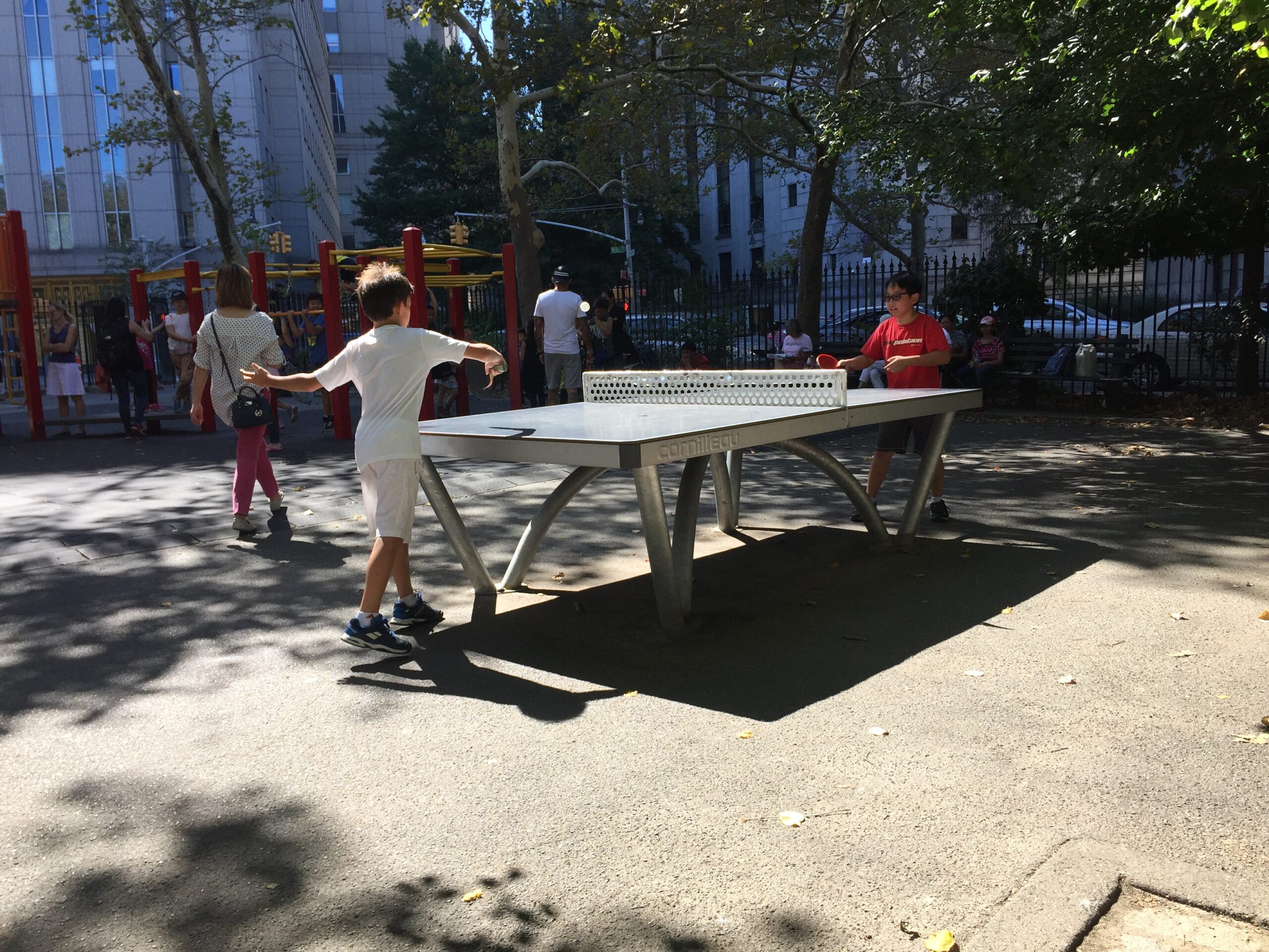 Kids play ping pong in a park outside