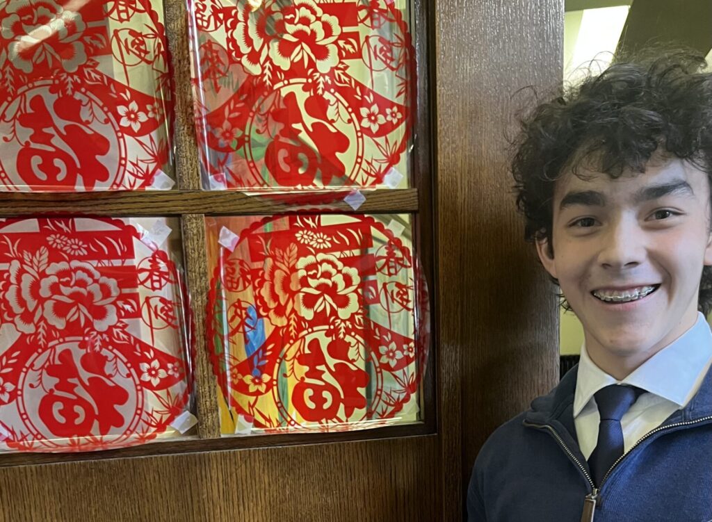 Virtual NSLI-Y Chinese participant alongside Chinese New Year window art provided by the program