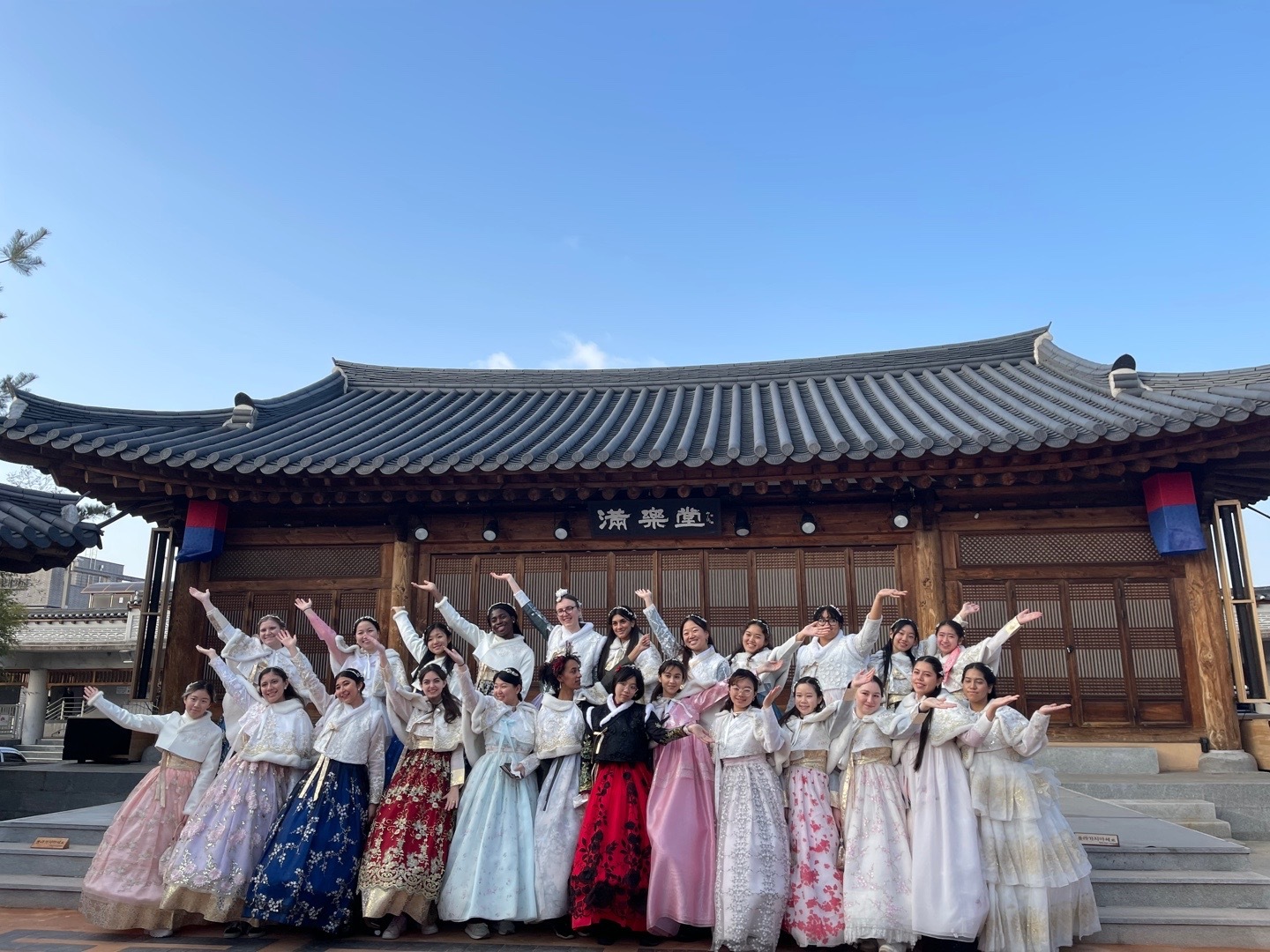 Jessey poses in traditional Hanbok in front of a Korean temple with members of her Alumni Traveller Program cohort.