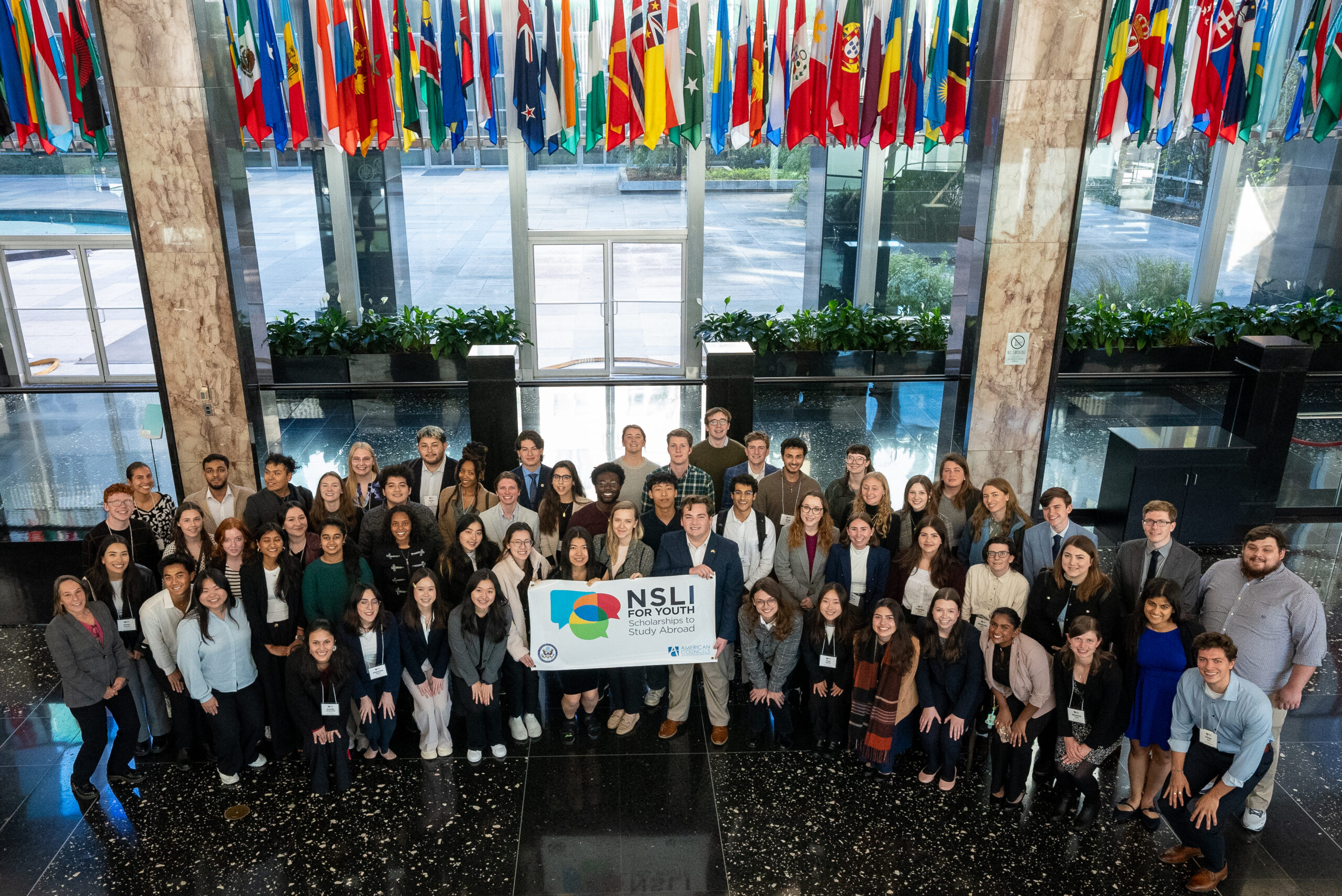 A large group poses with a NSLI-Y banner at the Department of State