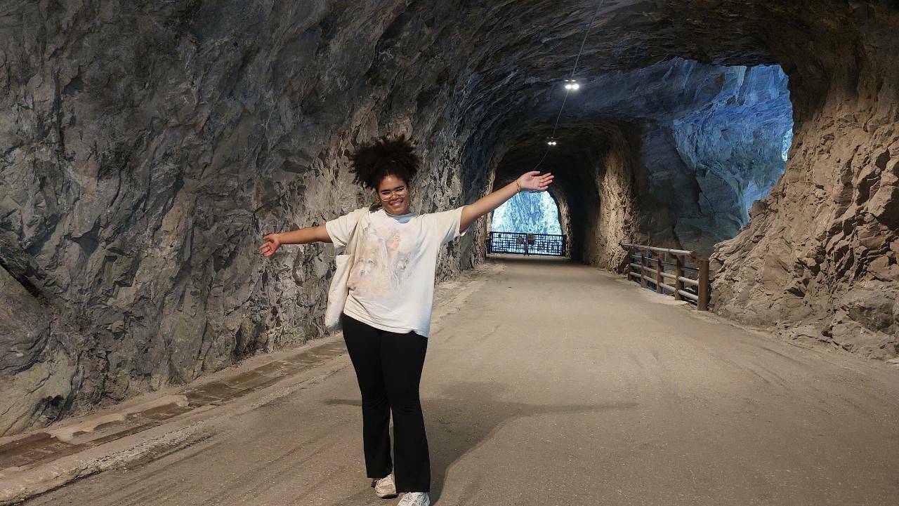Natasha standing at the opening of a cave.