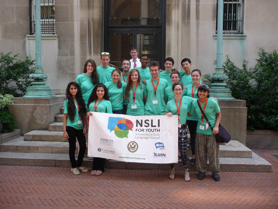 Image of NSLI-Y students in their NSLI-Y shirts posing with a NSLI-Y banner
