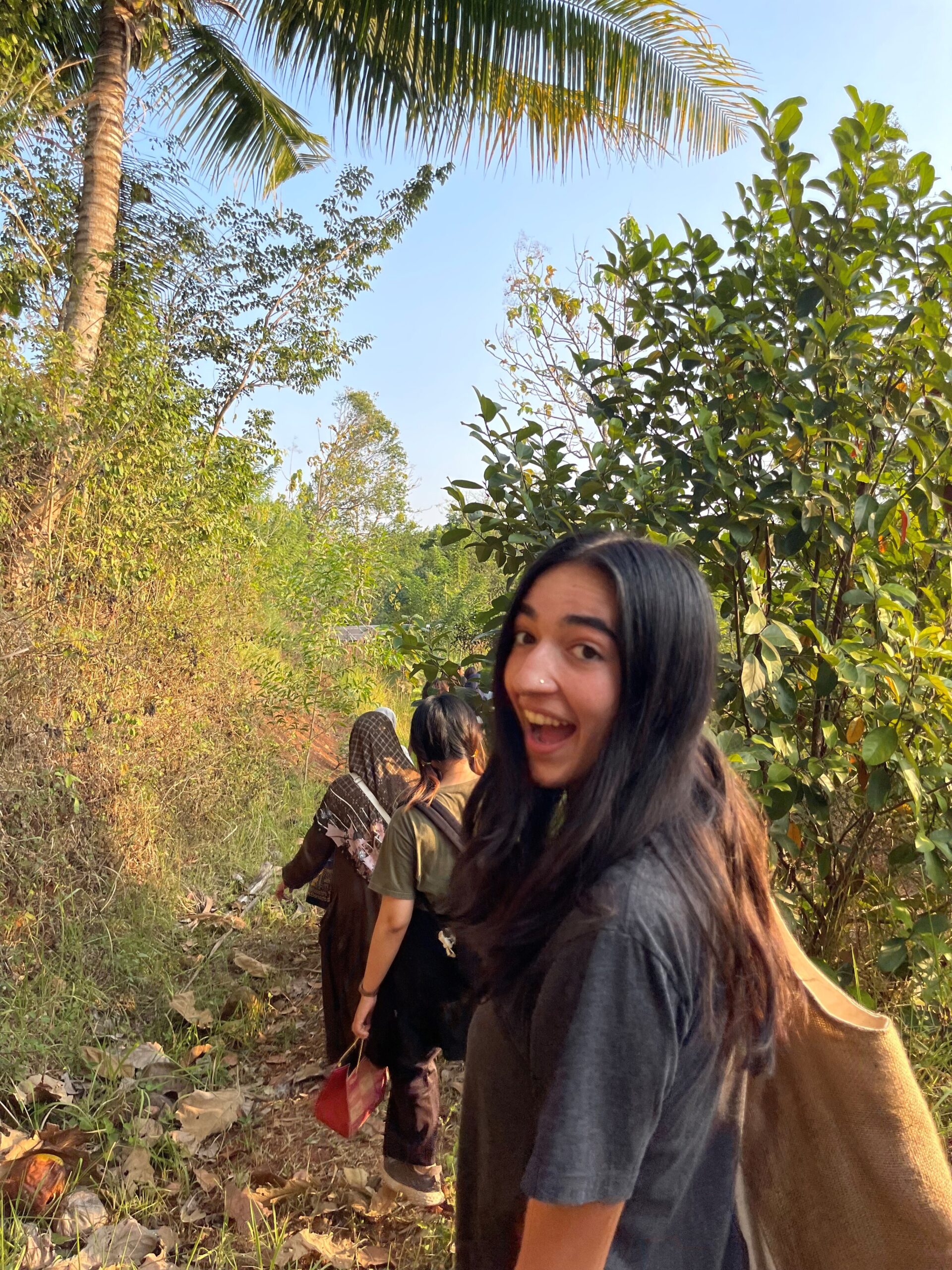 A student looks back at the camera as she walks along a forest path