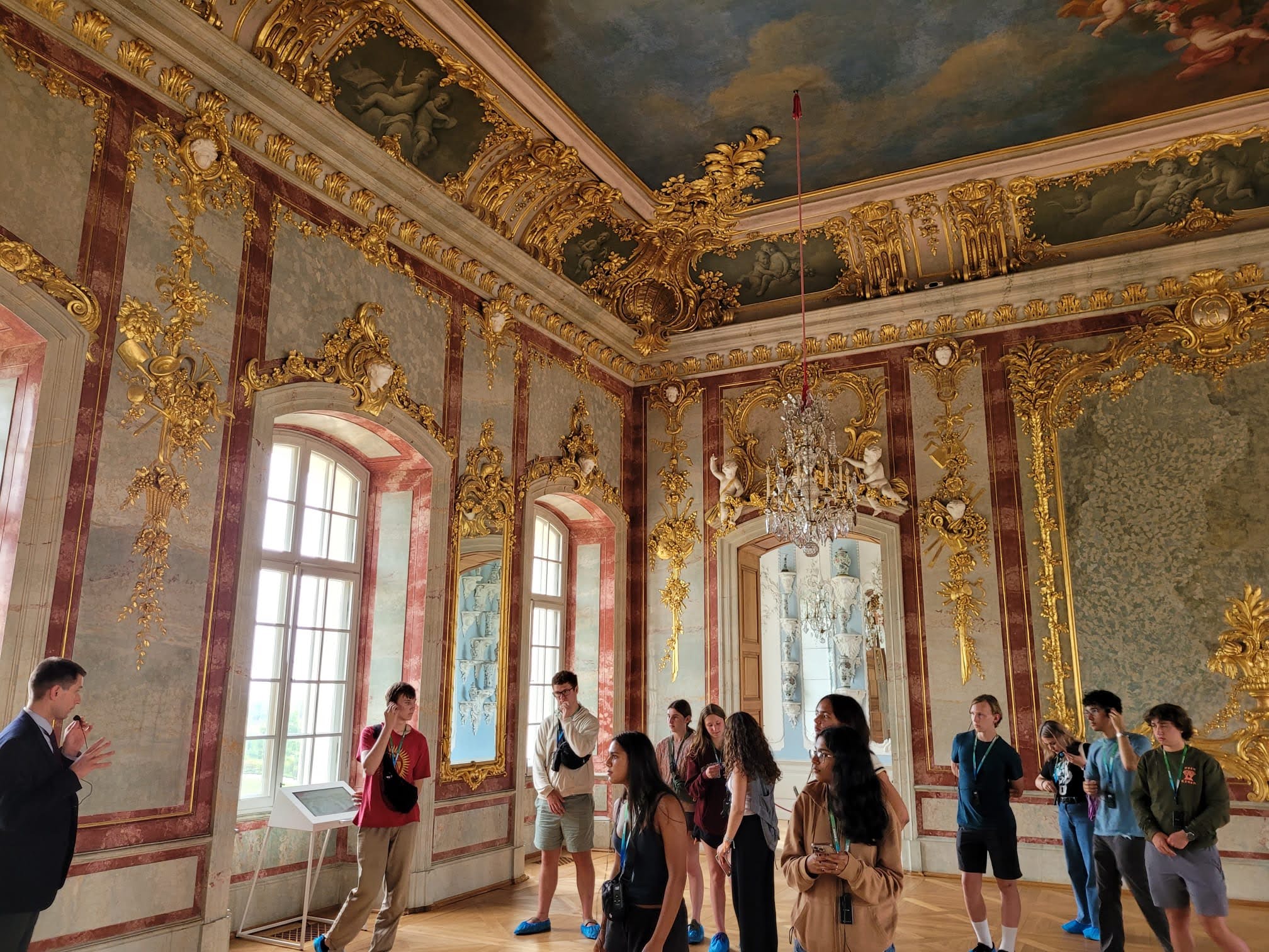 An image of students touring an opulent palace with extravagant gold trim