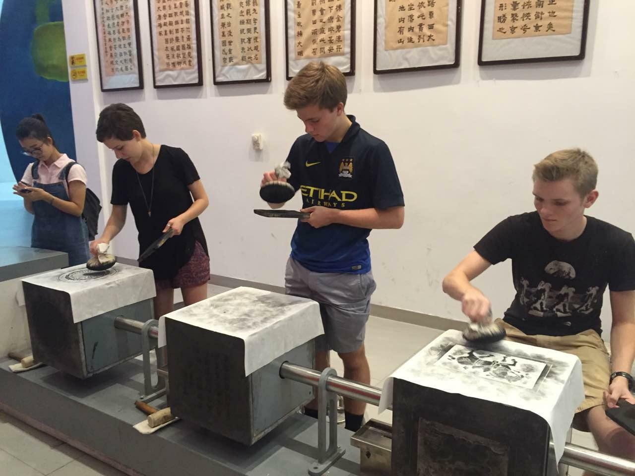 Four students are creating ink prints.