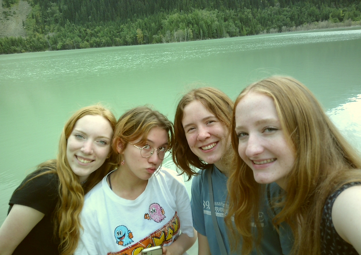 Four students smile for the camera in front a lake