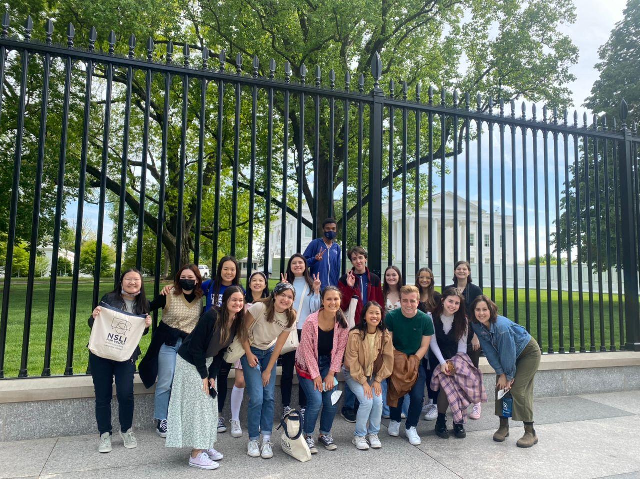 A group of students pose in front of the gate at the White House