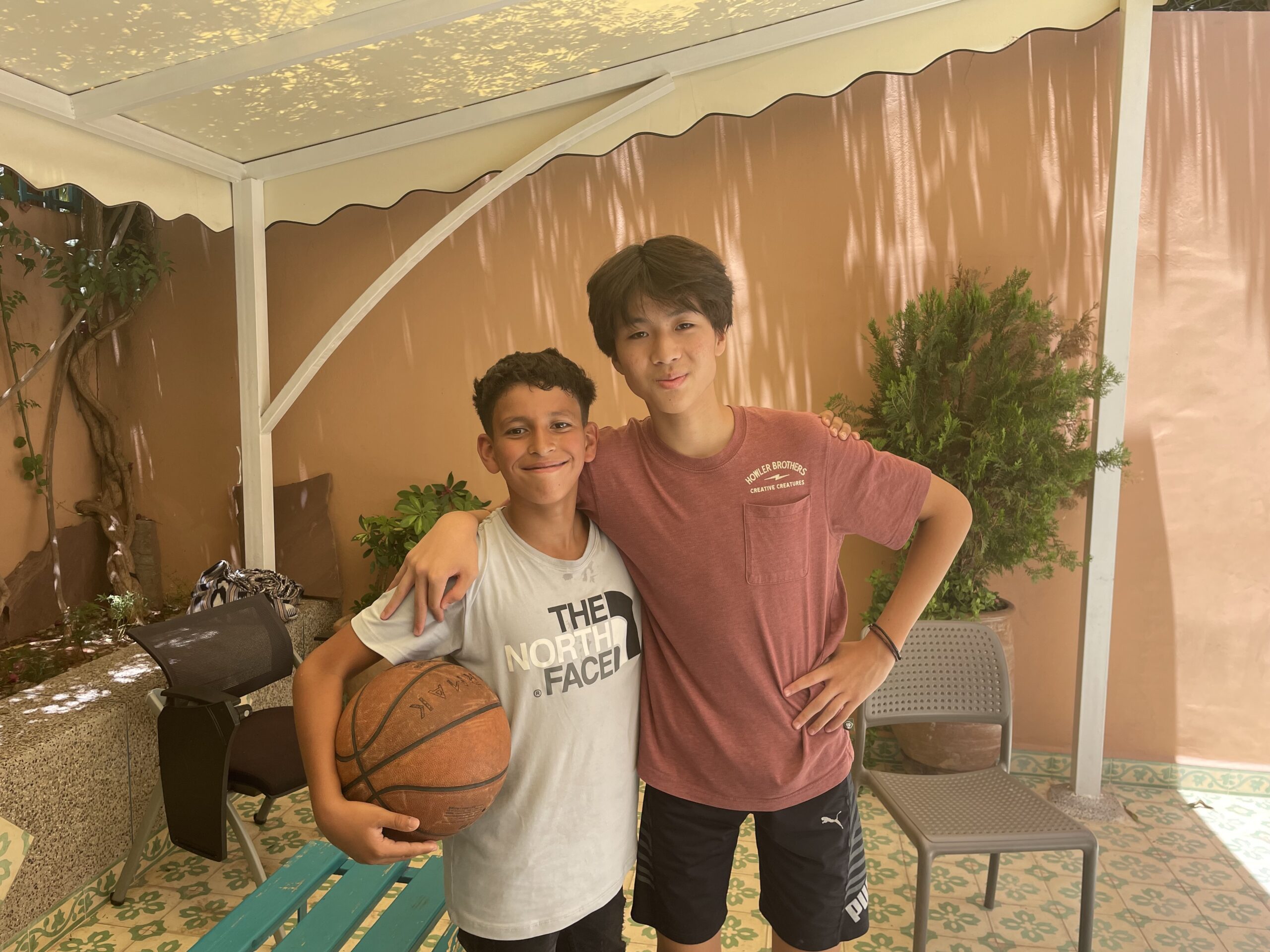 Two students smile for the camera with a basketball