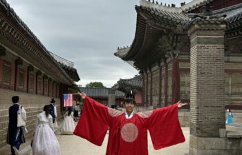A student wears traditional Korean dress while holding a small American flag