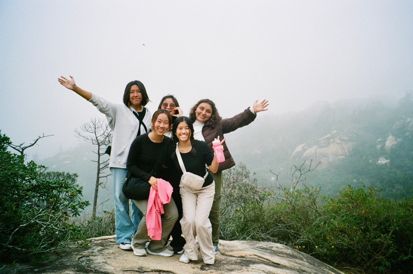 Students pose in front of a misty overlook on a hike