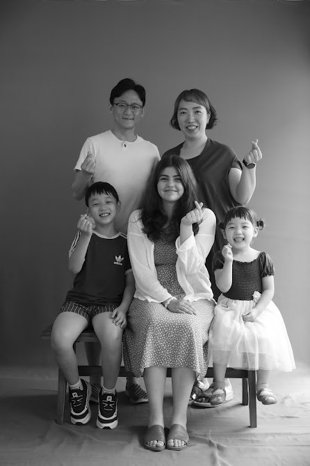 A black and white image of a student sitting for a portrait with her host family