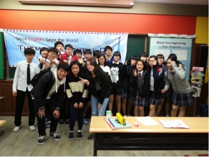 Image of Emily posing with a group of middle schoolers in a classroom