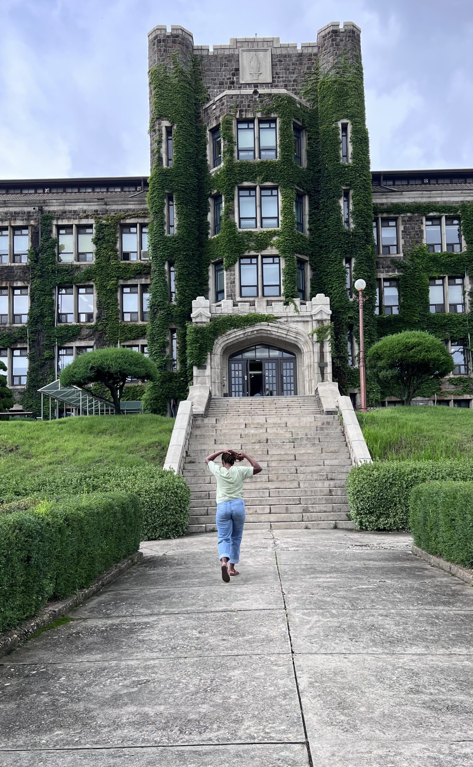 A student walks into a large, ivy covered building