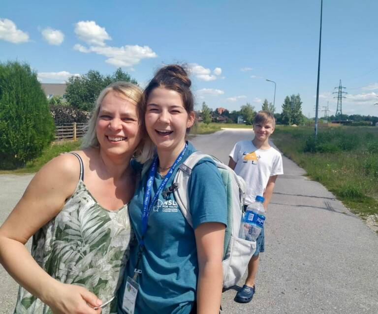 A high school female student and a middle-aged woman pose together with a young boy in the background