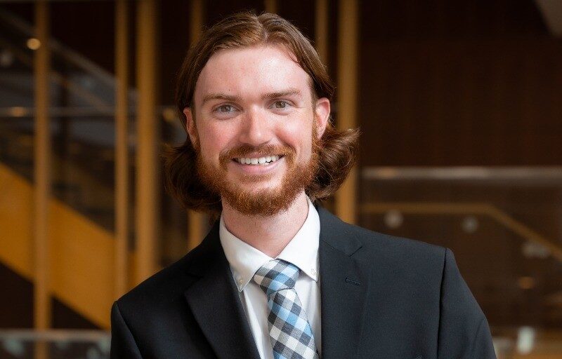 A young man in a suit poses for a headshot photo.